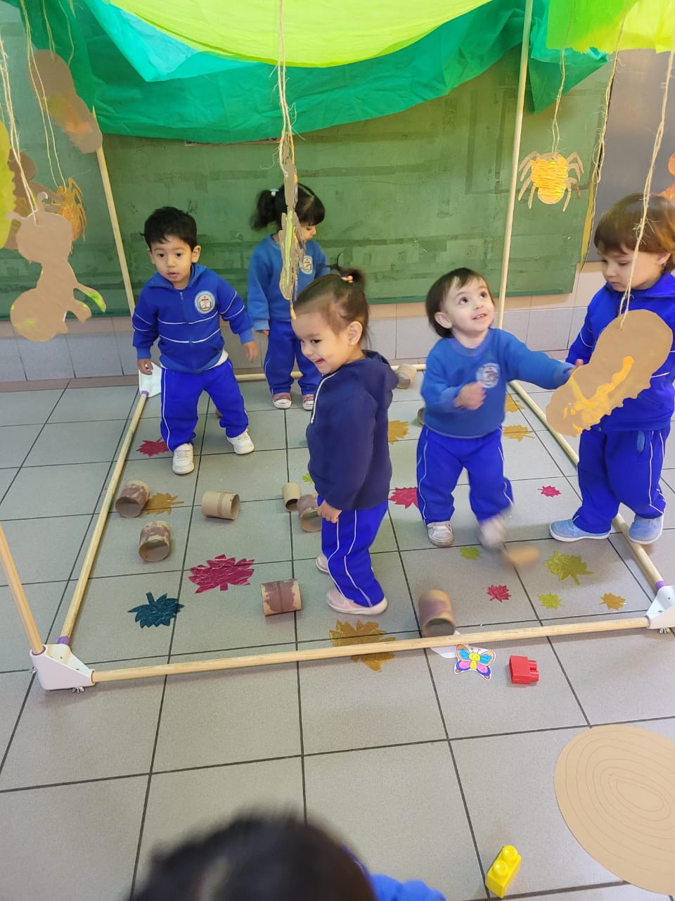 Niñas y niños de sala de 1 y 2 años jugando en un espacio ambientado como bosque
