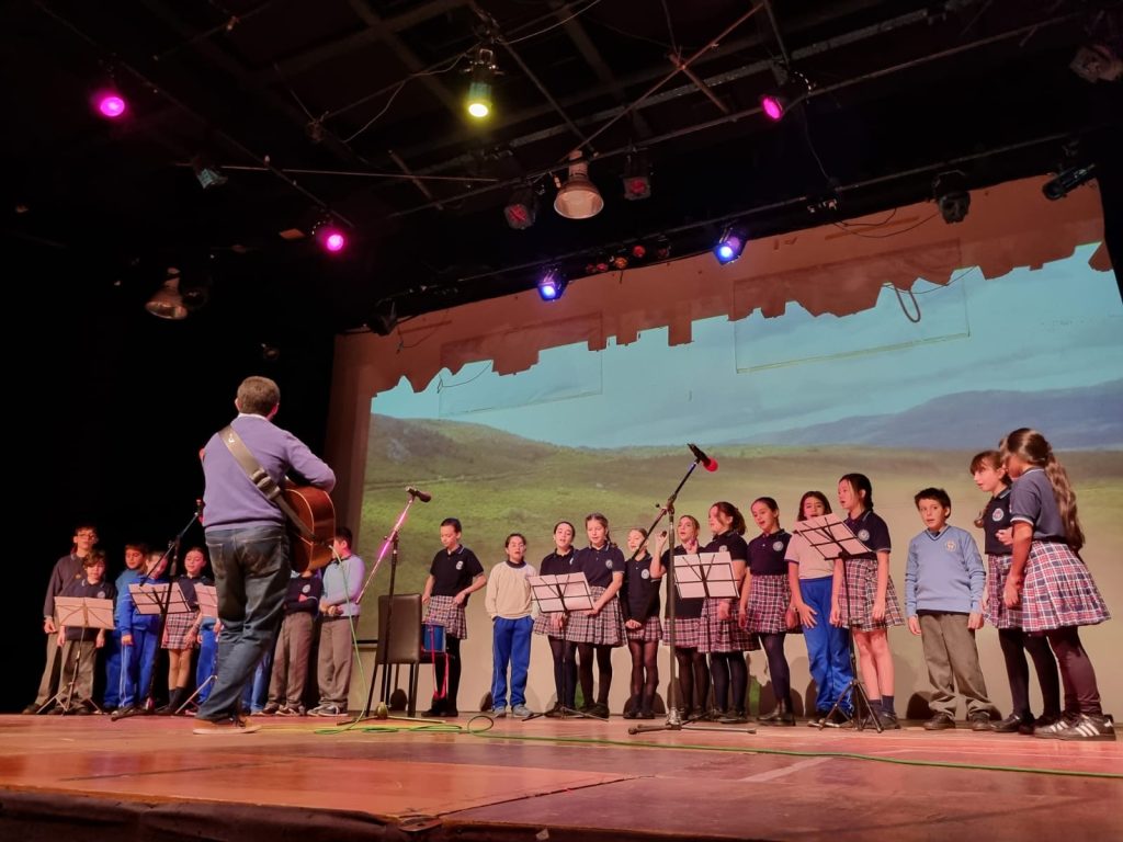 Estudiantes bailando en el escenario durante una muestra artística