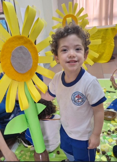 Niño del Nivel Inicial sonriendo entre girasoles de papel en una actividad sensorial