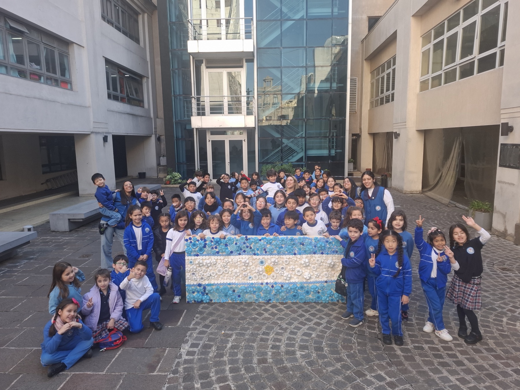 Estudiantes del Nivel Primario con una bandera argentina hecha con tapitas recicladas